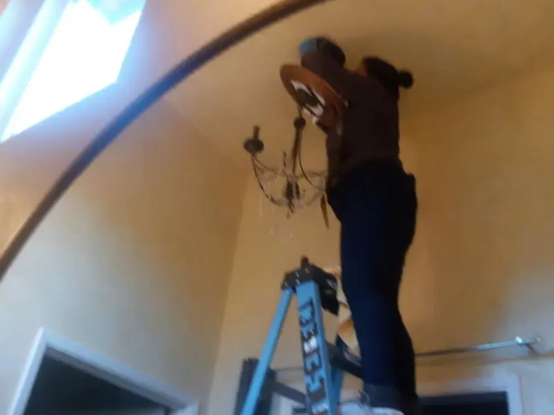 Electrician installing a chandelier in a Price residence